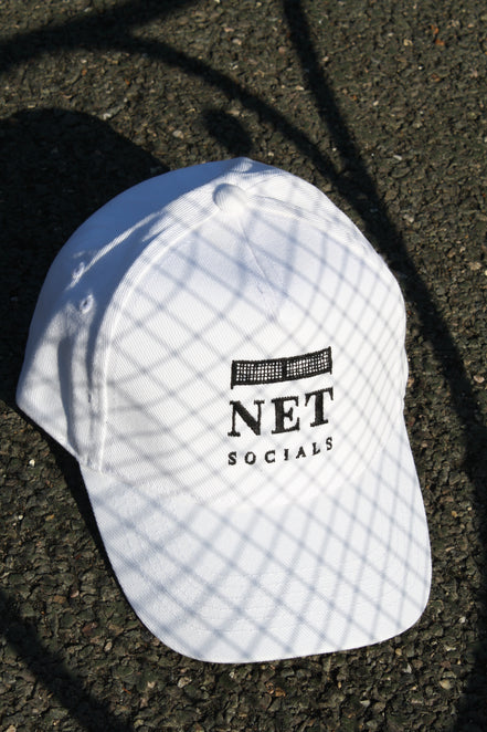 White cap with 'NET SOCIALS' logo on a dark surface